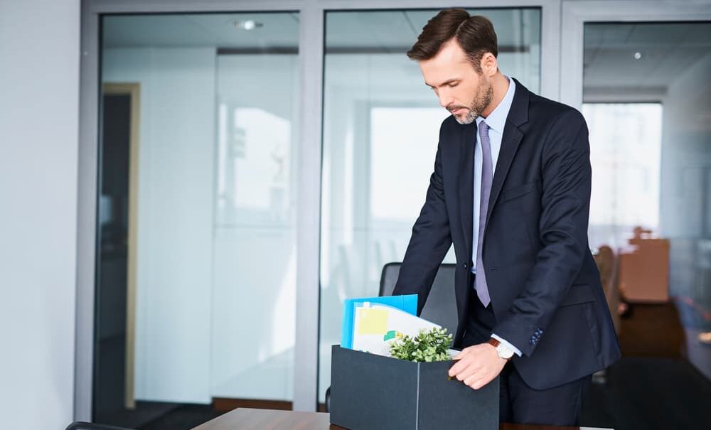 man packing up desk supplies into box after bring from job following a DUI