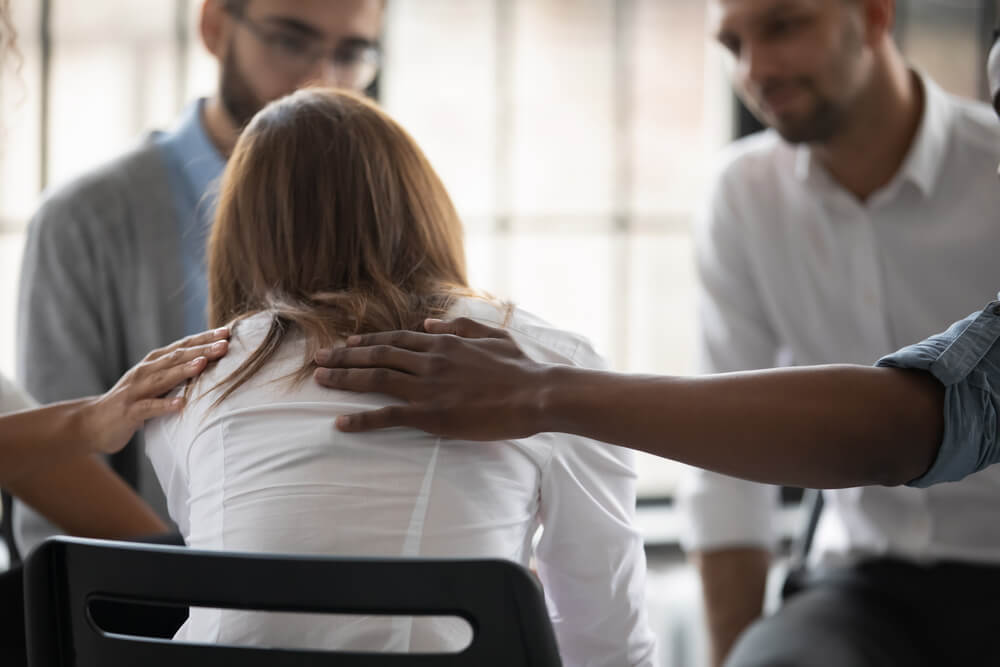 Close up back view unhappy woman with supporting diverse people at therapy session.