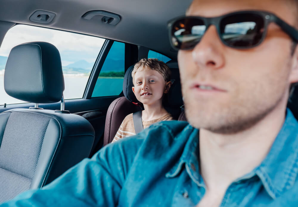 Father driving with child in backseat, illustrating DUI with minor passenger risk in Colorado